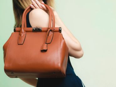 Woman holding a stylish brown leather handbag over her shoulder.